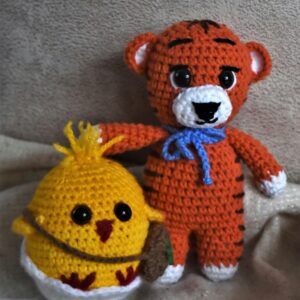 Adorable handmade knitted tiger and chick plush toys on a soft background.
