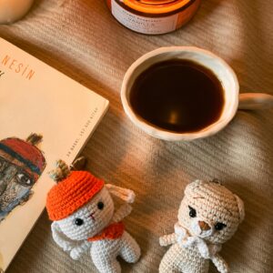 Warm and inviting setting with a cup of coffee, candles, and handmade crochet toys.
