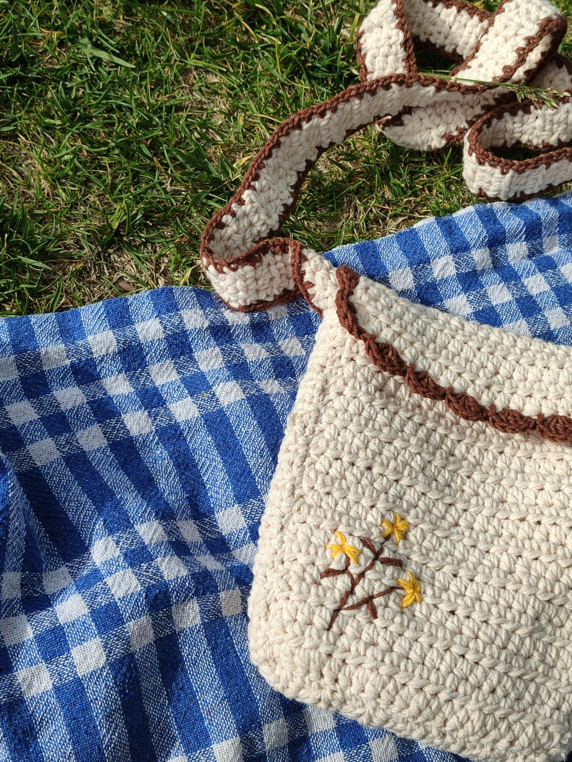 Close-up of a crochet bag on a blue checkered blanket, showcasing its handmade charm.