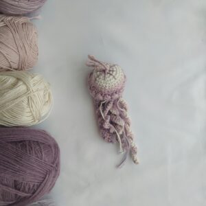 Colorful crochet jellyfish surrounded by skeins of yarn on a flatlay.